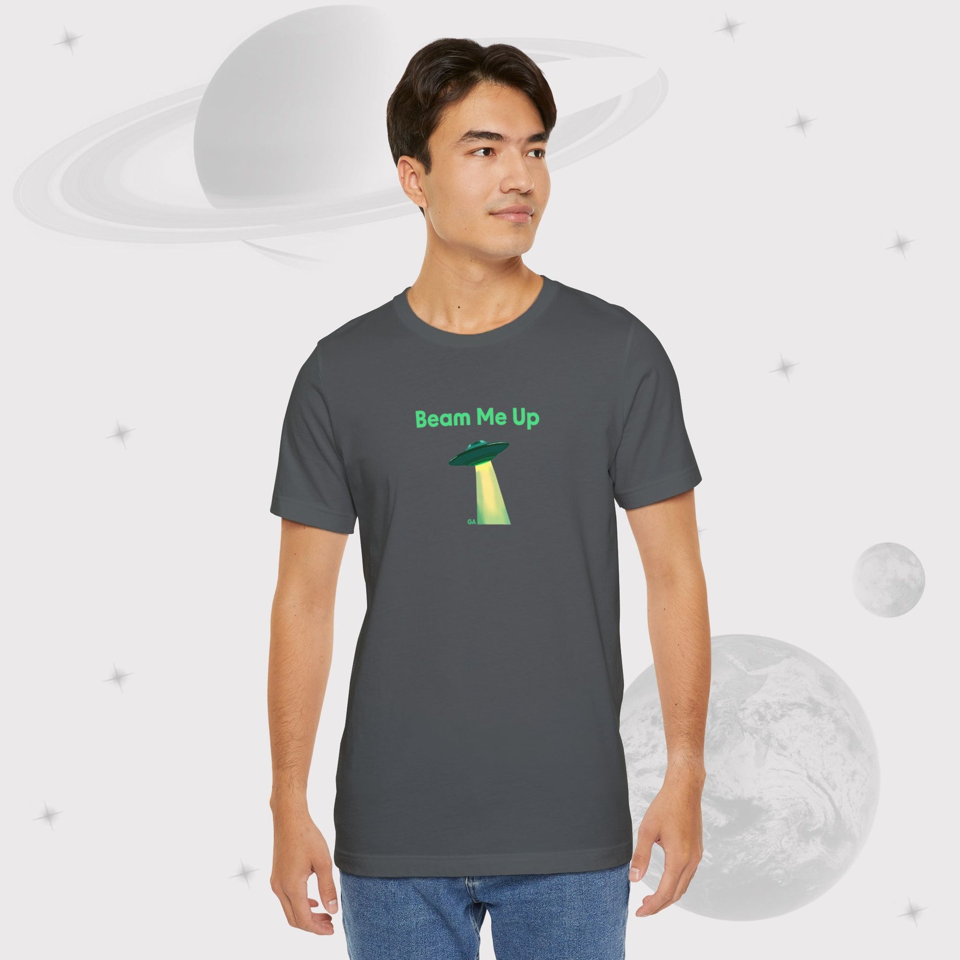 Guy wearing Going Across men's basic t-shirt in asphalt/grey, with jeans, featuring the text ‘Beam Me Up’ and space art of ufo in celestial green by Manharleen.