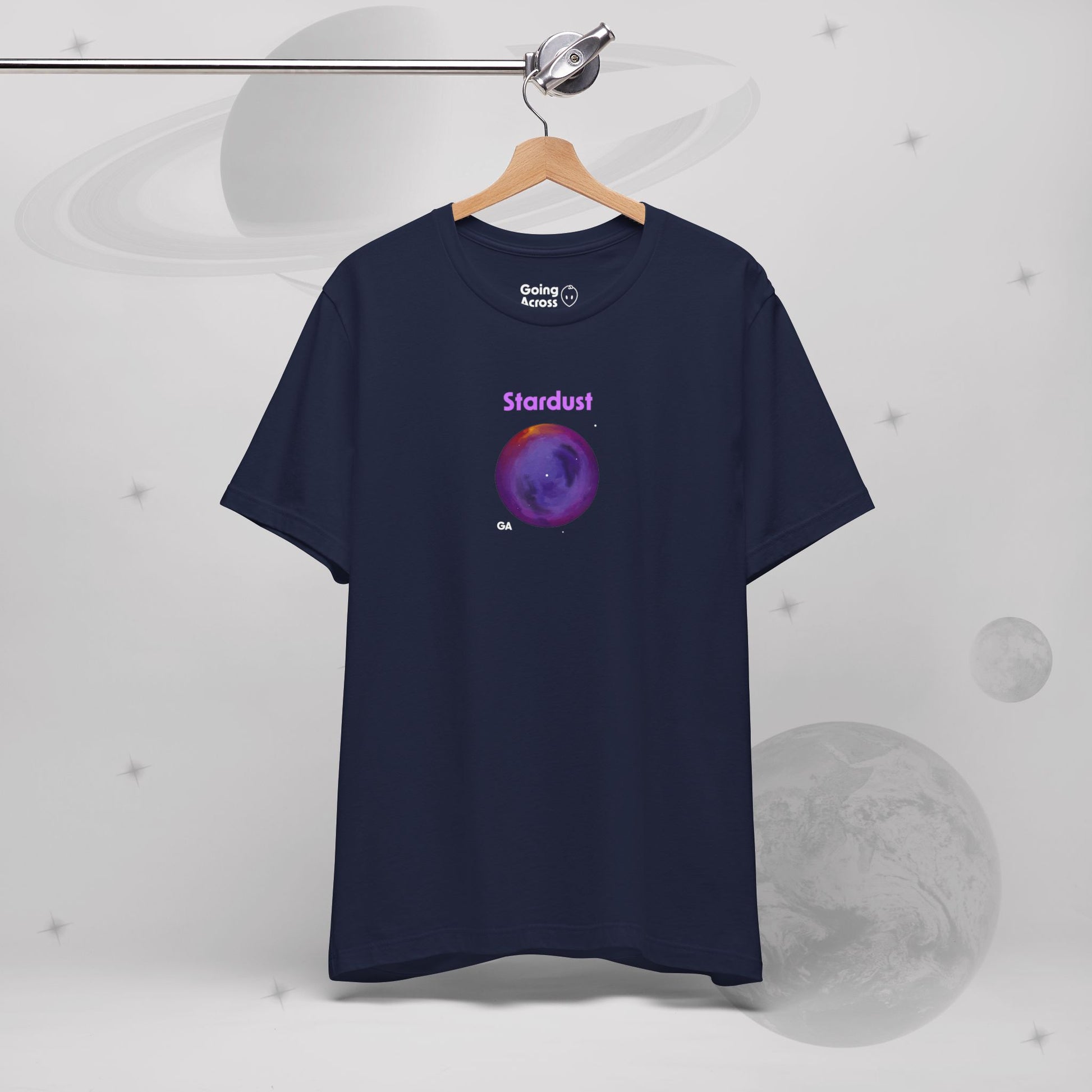 Going Across women's basic t-shirt in navy hanging, featuring the text ‘Stardust’ with space art of bright purple nebula by Manharleen.