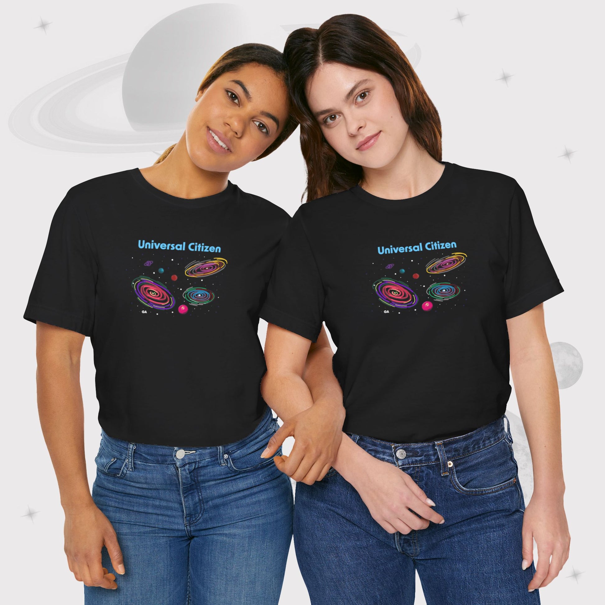 Two women wearing Going Across women's basic t-shirt in black, featuring the text ‘Universal Citizen’ with space art of vibrant galaxies and planets by Manharleen.