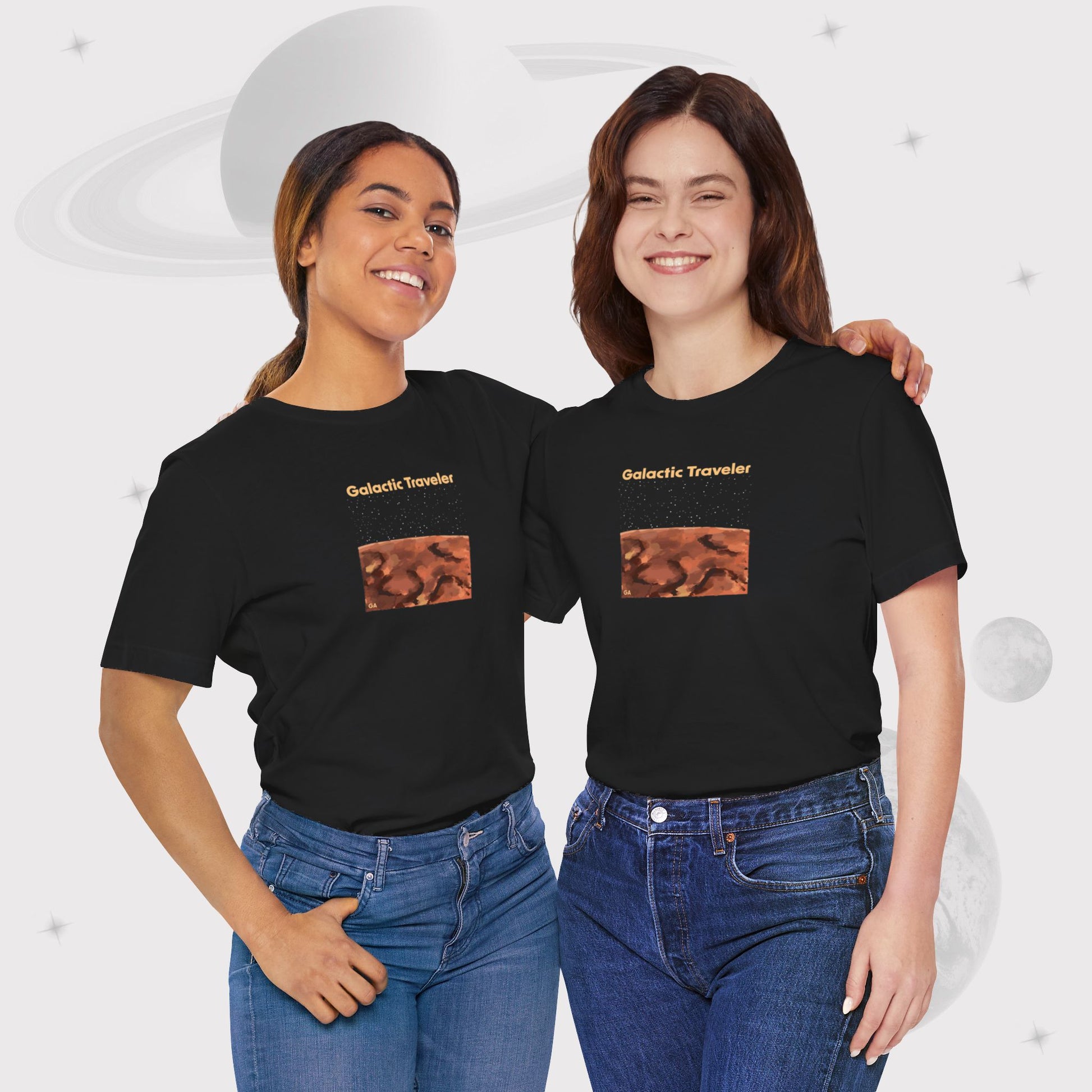 Two women wearing Going Across women's basic t-shirt in black, featuring the text ‘Galactic Traveler’ with space art of a red planet and a starry sky by Manharleen.