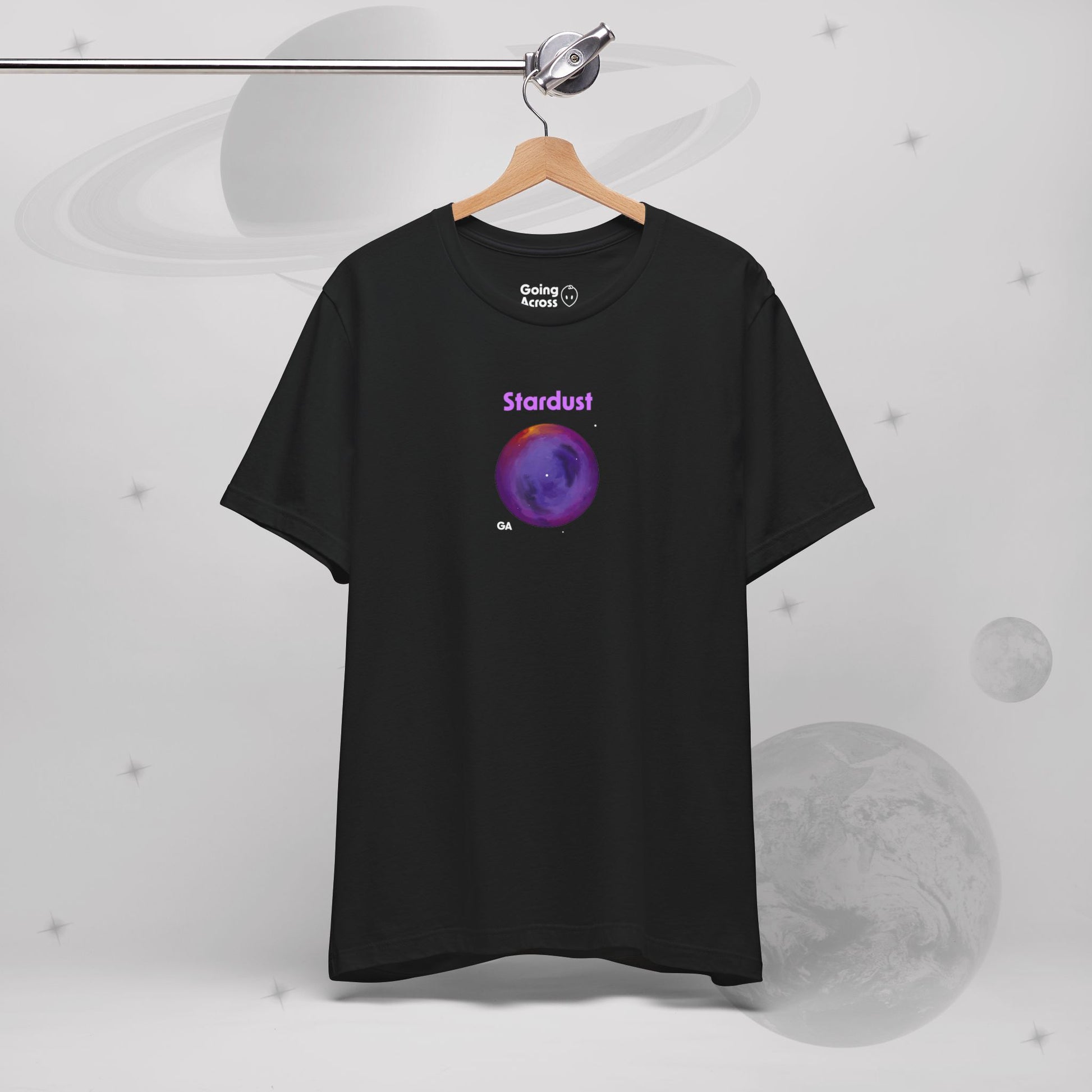 Going Across women's basic t-shirt in black hanging, featuring the text ‘Stardust’ with space art of bright purple nebula by Manharleen.