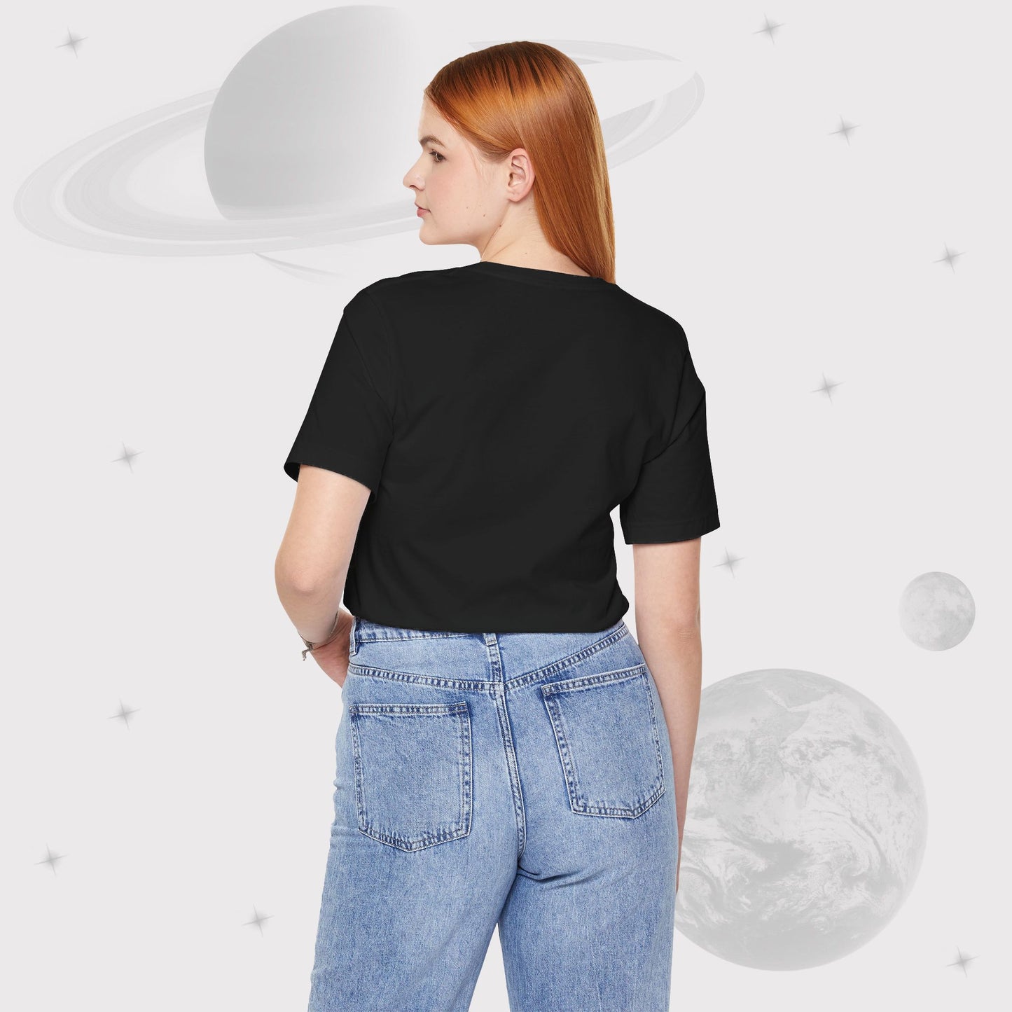 Back side of Woman wearing Going Across women's basic t-shirt in black with high waist jeans, featuring the text ‘Find Your Orbit’ with space art of an orbit and a starry sky by Manharleen.