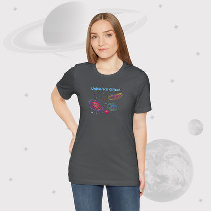 Woman wearing Going Across women's basic t-shirt in asphalt/gray with jeans, featuring the text ‘Universal Citizen’ with space art of vibrant galaxies and planets by Manharleen.