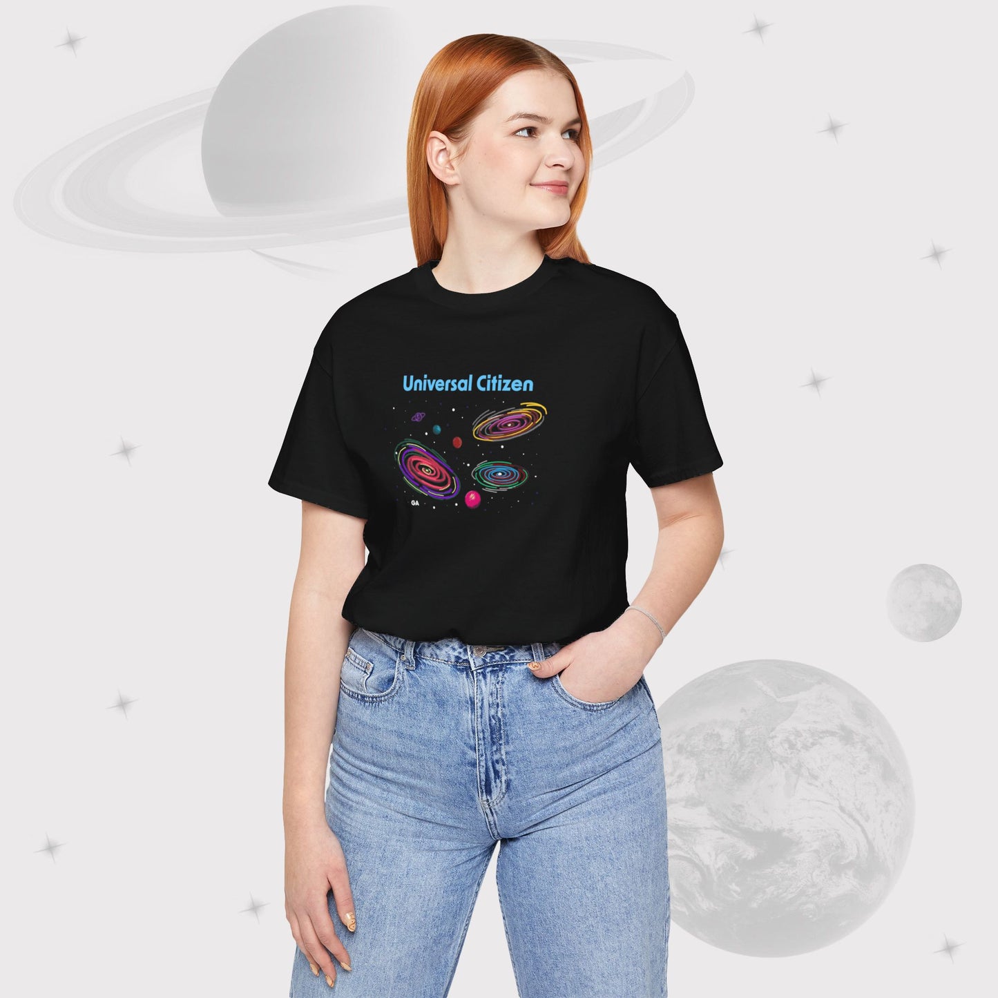 Woman wearing Going Across women's basic t-shirt in black with high waisted jeans, featuring the text ‘Universal Citizen’ with space art of vibrant galaxies and planets by Manharleen.