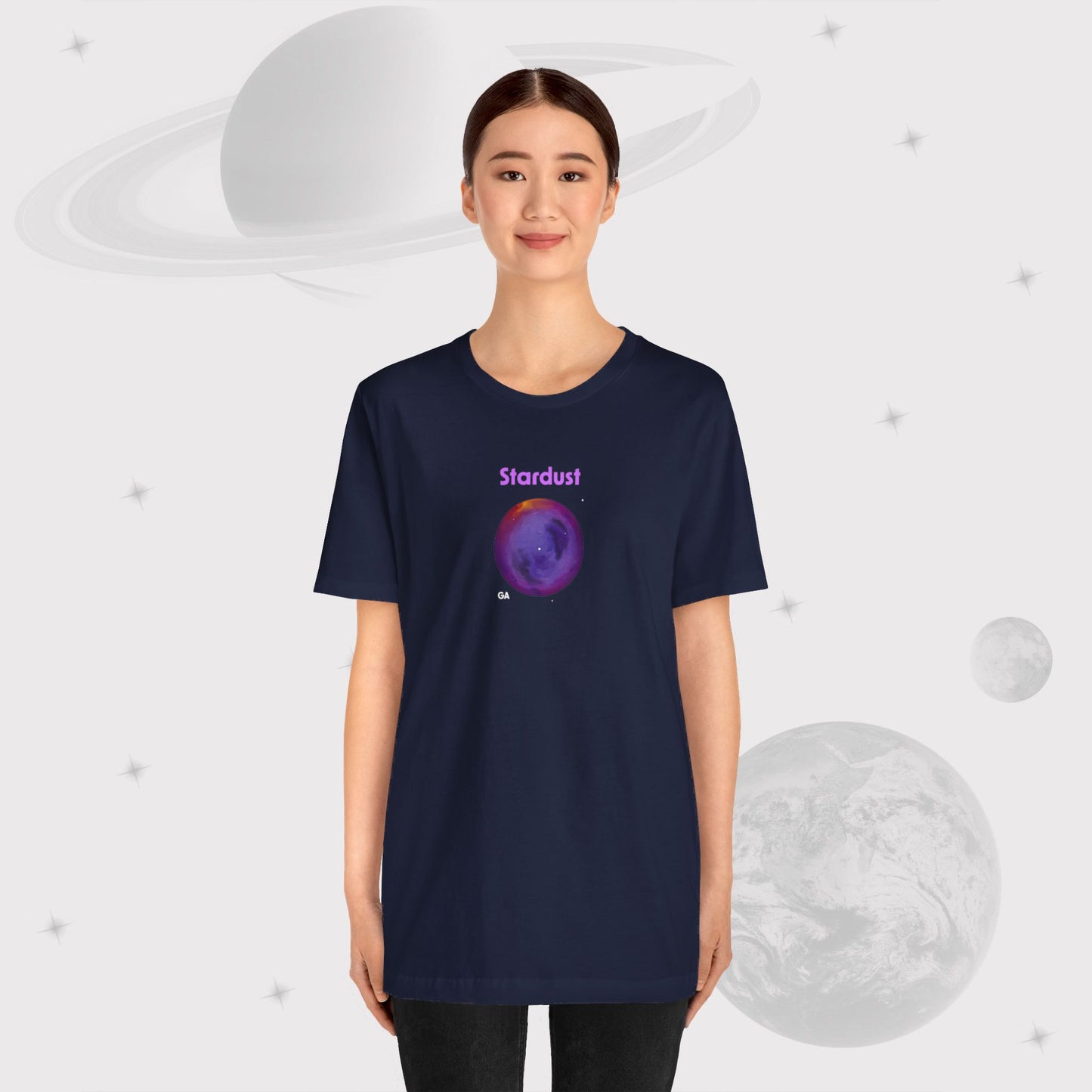 Woman wearing Going Across women's basic t-shirt in navy with pants, featuring the text ‘Stardust’ with space art of bright purple nebula by Manharleen.