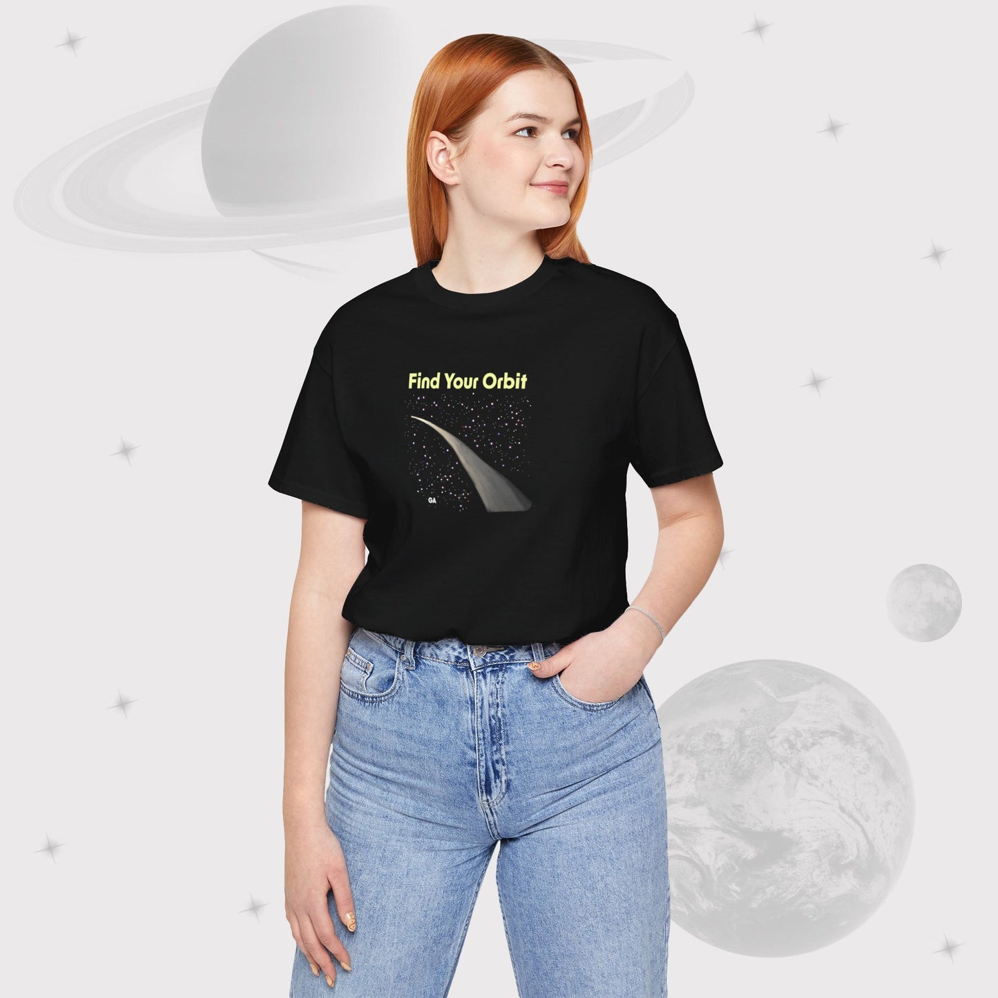 Woman wearing Going Across women's basic t-shirt in black with high waist jeans, featuring the text ‘Find Your Orbit’ with space art of an orbit and a starry sky by Manharleen.