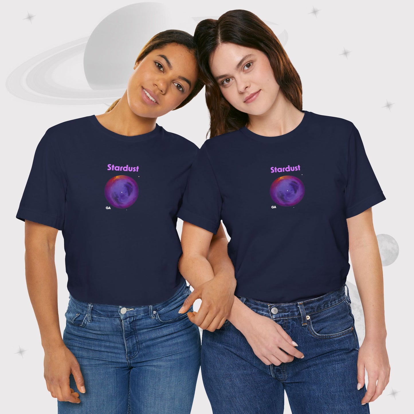 Two women wearing Going Across women's basic t-shirt in navy with high waist jeans, featuring the text ‘Stardust’ with space art of bright purple nebula by Manharleen.