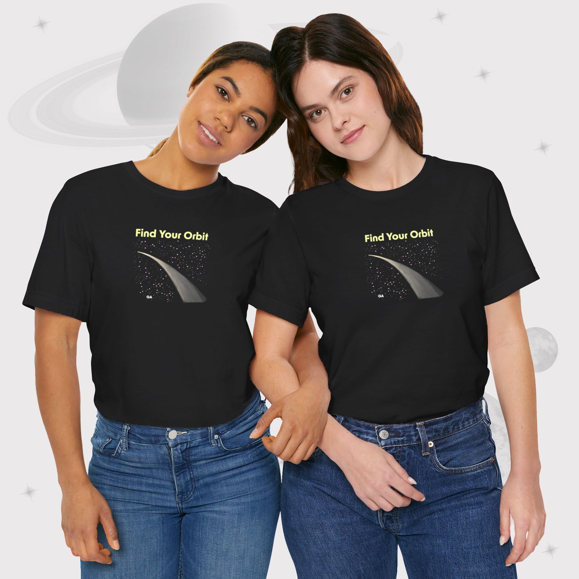 Two women wearing Going Across women's basic t-shirt in black with high waist jeans, featuring the text ‘Find Your Orbit’ with space art of an orbit and a starry sky by Manharleen.