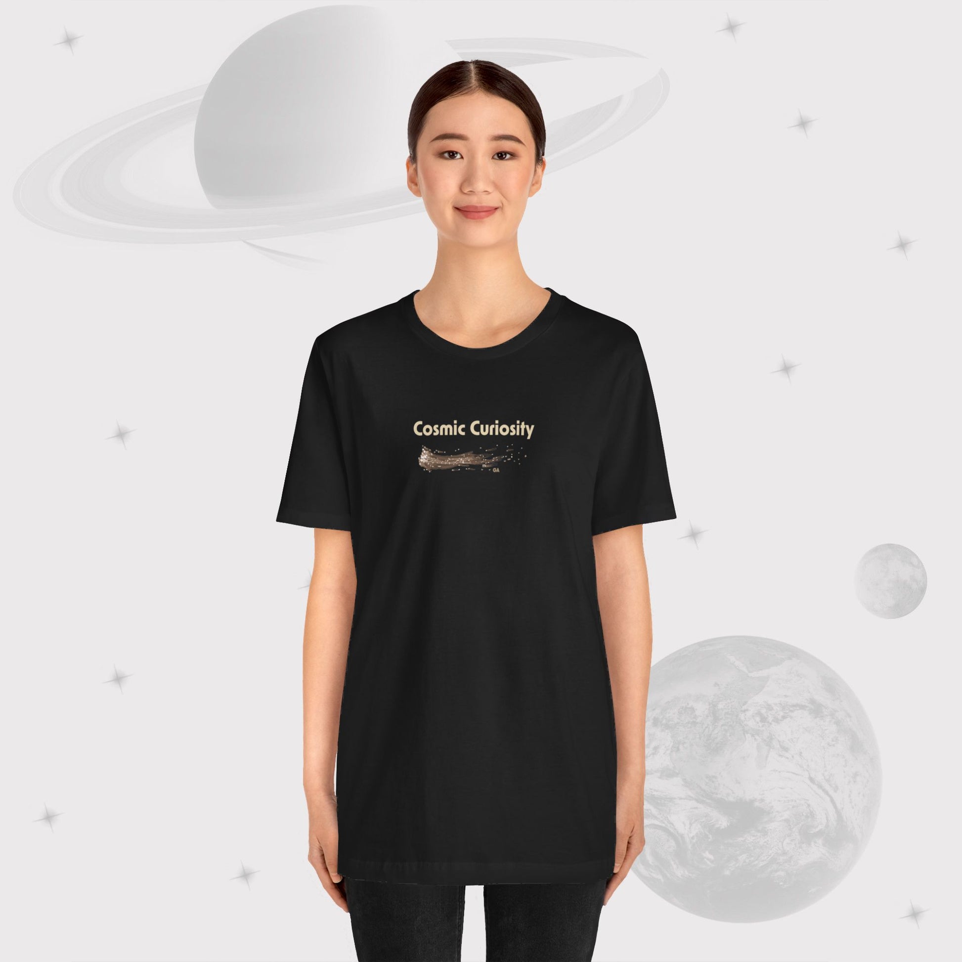 Girl wearing Going Across women's basic t-shirt in black, featuring the text ‘Cosmic Curiosity’ with space art of shooting stars by Manharleen.