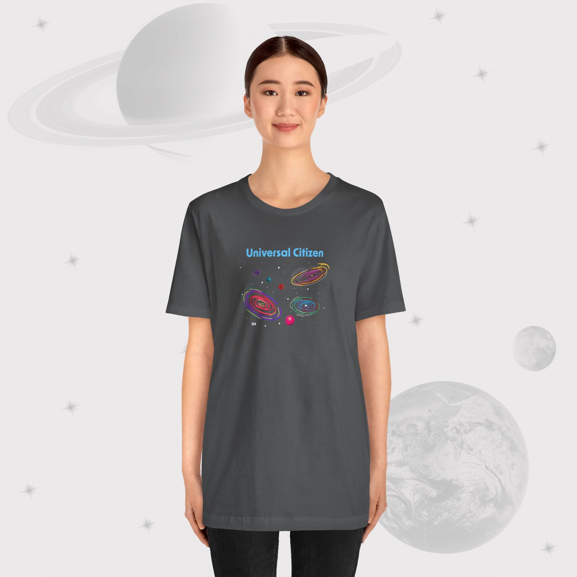 Guy wearing Going Across women's basic t-shirt in asphalt/gray, featuring the text ‘Universal Citizen’ with space art of vibrant galaxies and planets by Manharleen.