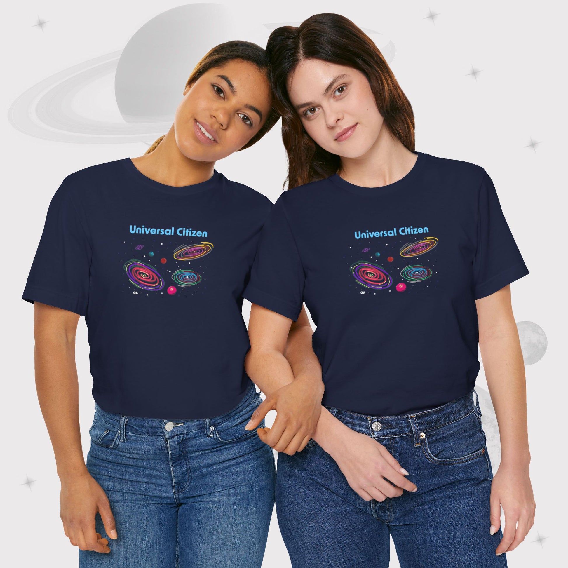 Two women wearing Going Across women's basic t-shirt in navy with jeans, featuring the text ‘Universal Citizen’ with space art of vibrant galaxies and planets by Manharleen.