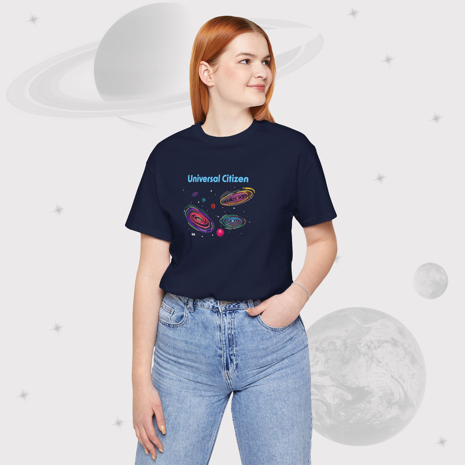 Woman wearing Going Across women's basic t-shirt in navy with jeans, featuring the text ‘Universal Citizen’ with space art of vibrant galaxies and planets by Manharleen.