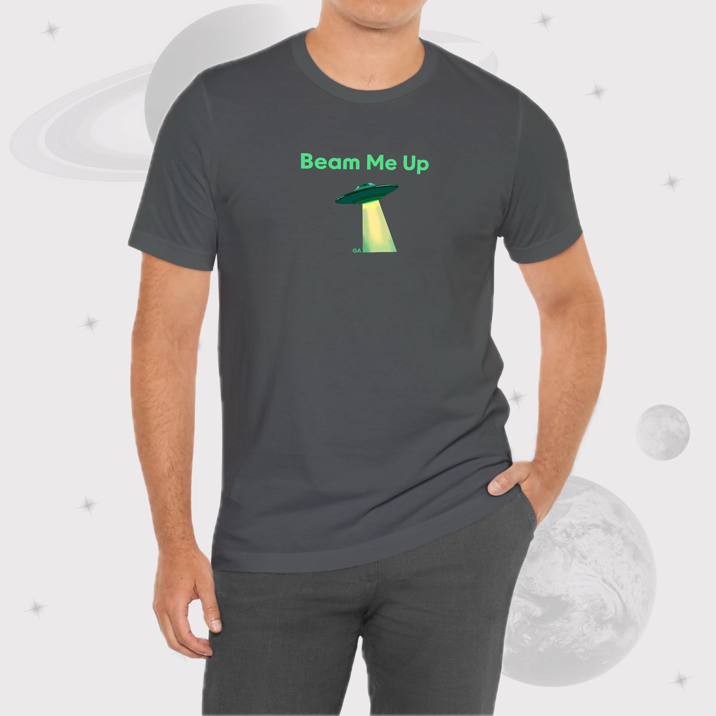 Man wearing Going Across men's basic t-shirt in asphalt, with jeans, featuring the text ‘Beam Me Up’ and space art of ufo in celestial green by Manharleen.