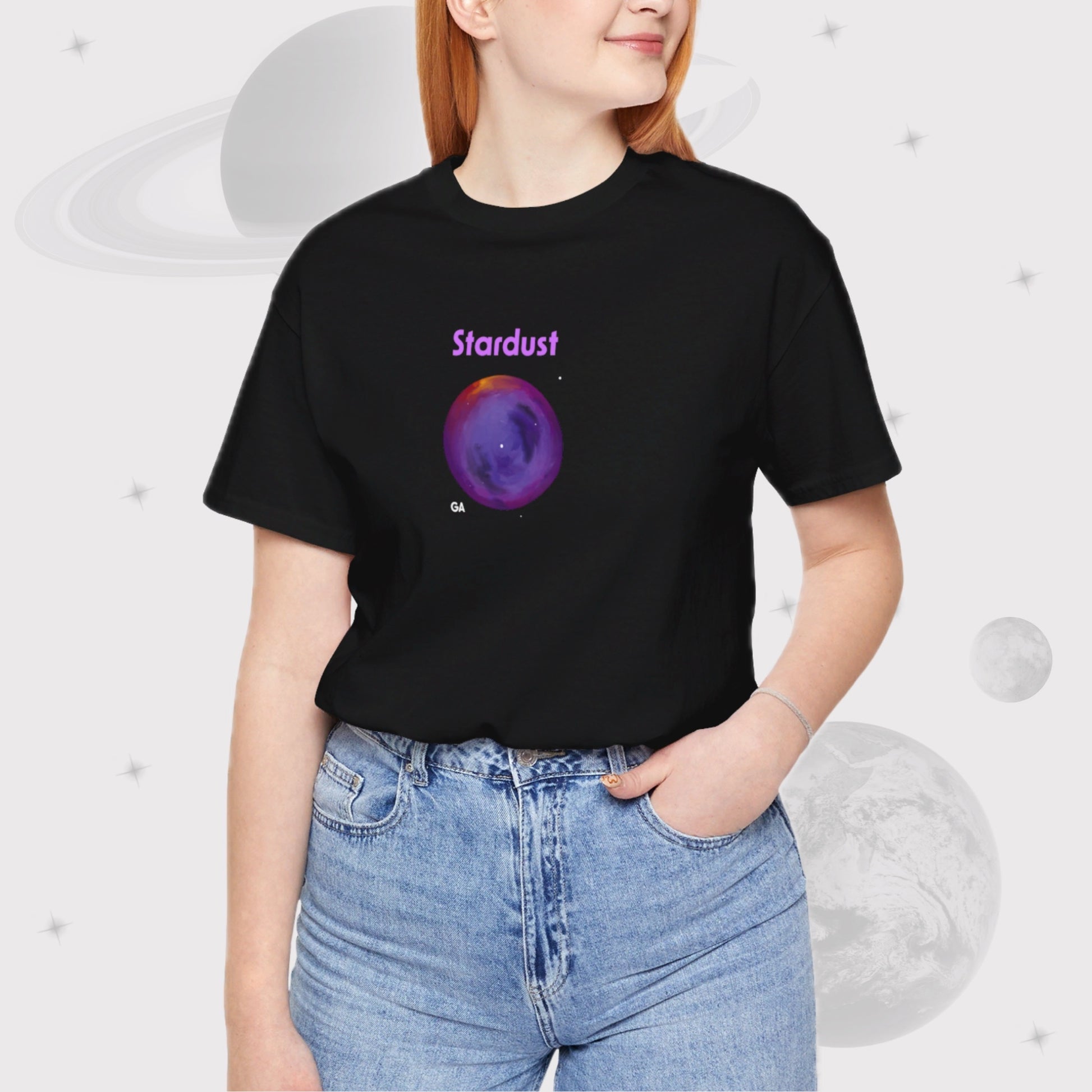 Woman wearing Going Across women's basic t-shirt in black, featuring the text ‘Stardust’ with space art of bright purple nebula.