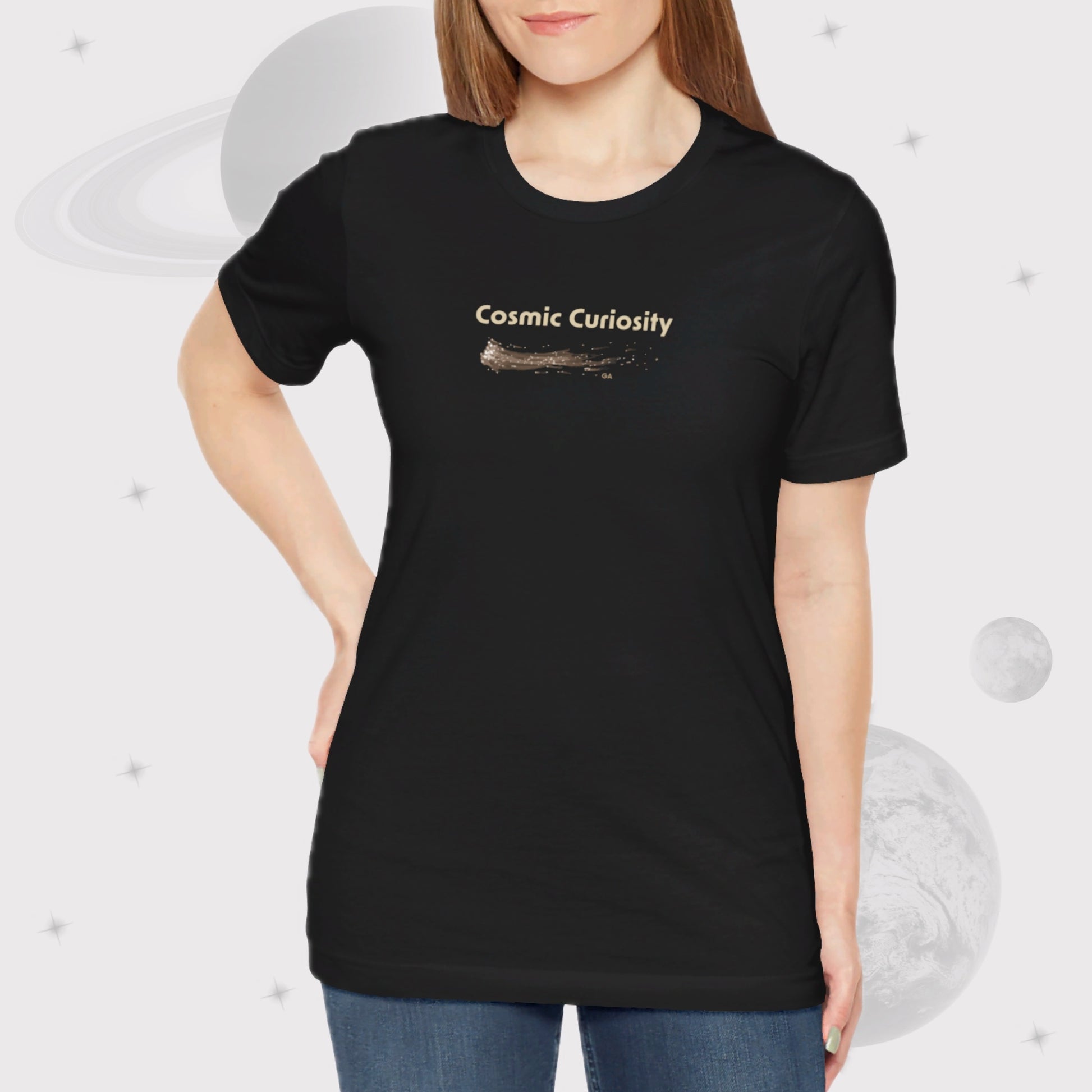 Woman wearing Going Across women's basic t-shirt in black, featuring the text ‘Cosmic Curiosity’ with space art of shooting stars.