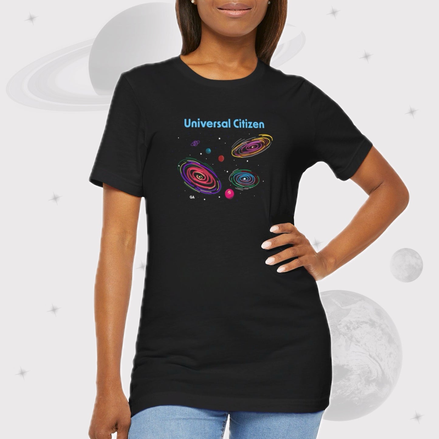 Woman wearing Going Across women's basic t-shirt in black with high waisted jeans, featuring the text ‘Universal Citizen’ with space art of vibrant galaxies and planets.