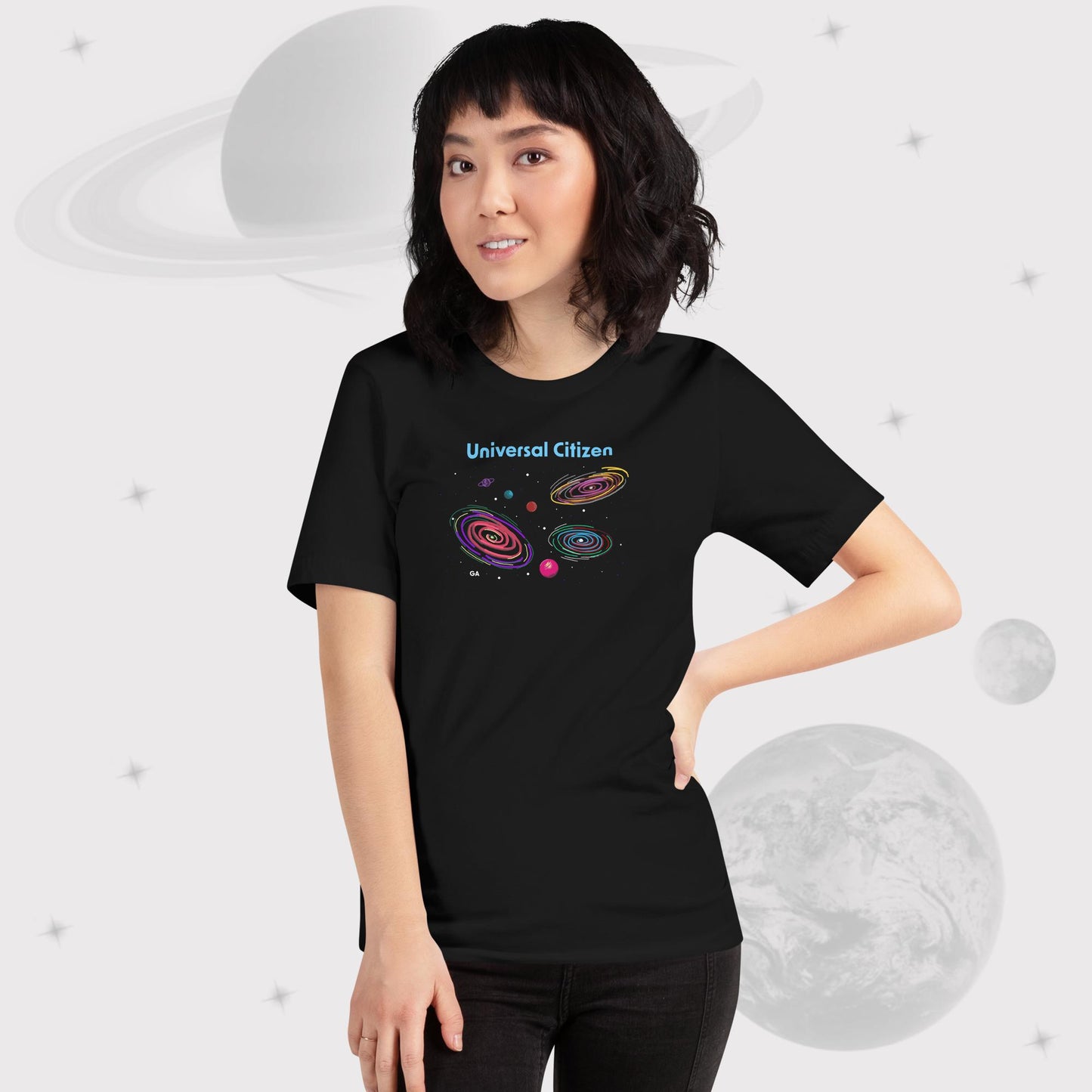 Woman wearing Going Across women's basic t-shirt in black with pants, featuring the text ‘Universal Citizen’ with space art of vibrant galaxies and planets by Manharleen.