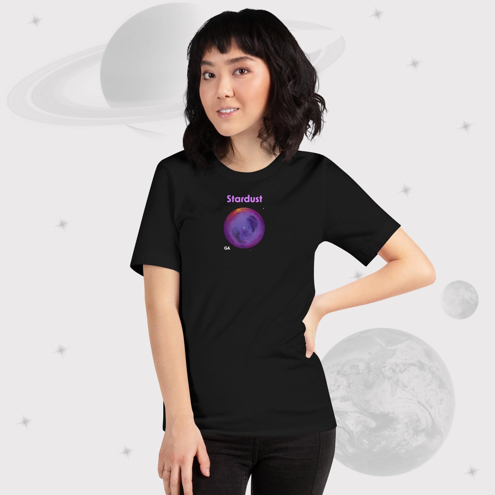 Woman wearing Going Across women's basic t-shirt in black with jeans, featuring the text ‘Stardust’ with space art of bright purple nebula by Manharleen.