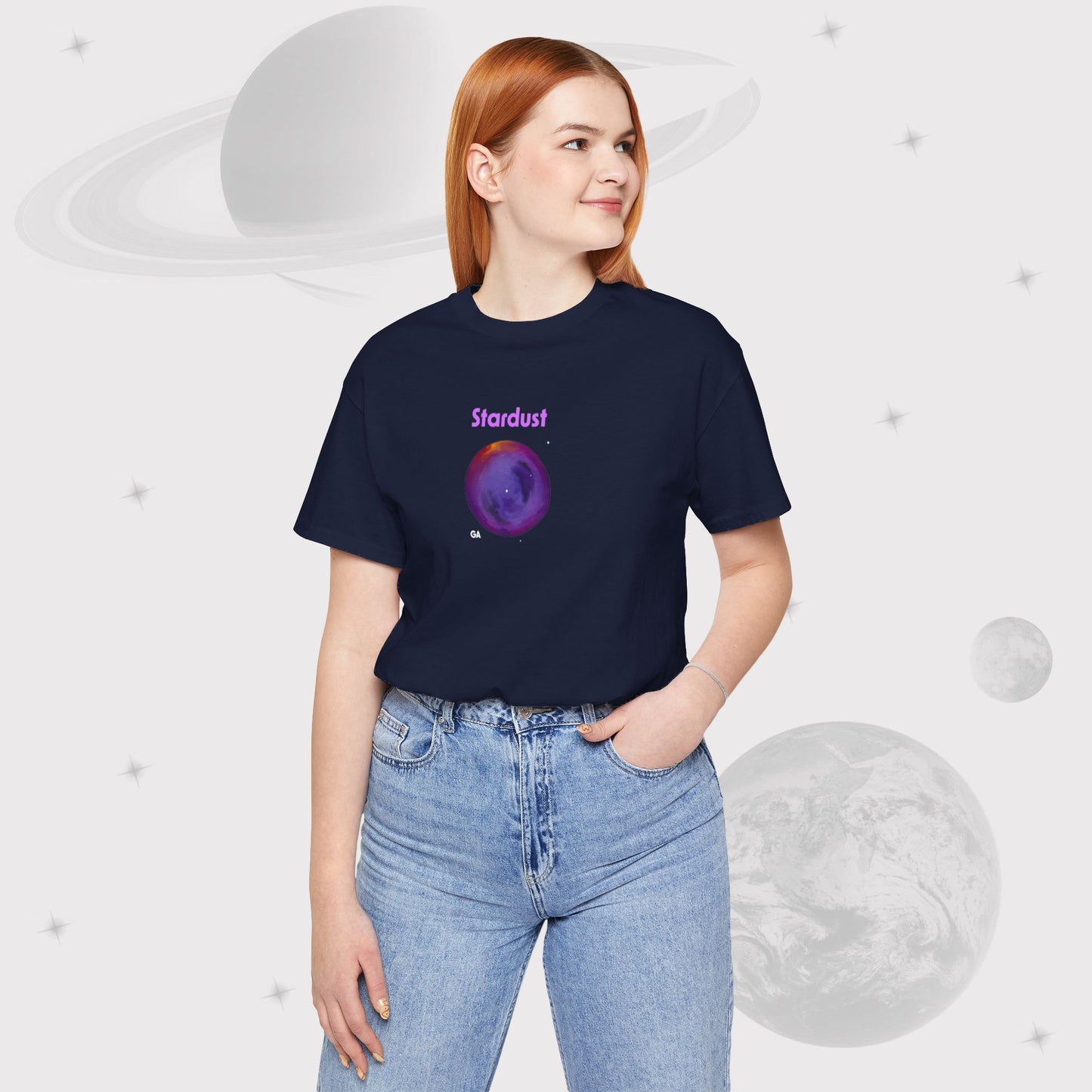 Woman wearing Going Across women's basic t-shirt in navy with high waist jeans, featuring the text ‘Stardust’ with space art of bright purple nebula by Manharleen.